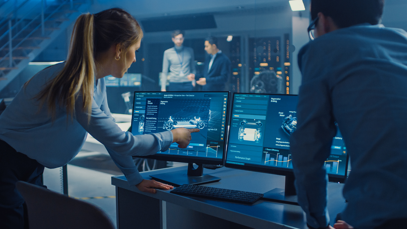 Woman leaning over monitors explaining what is on screen