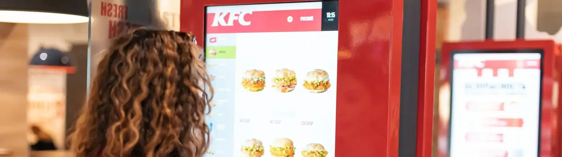 Customer browsing menu options on KFC self-service kiosk touchscreen