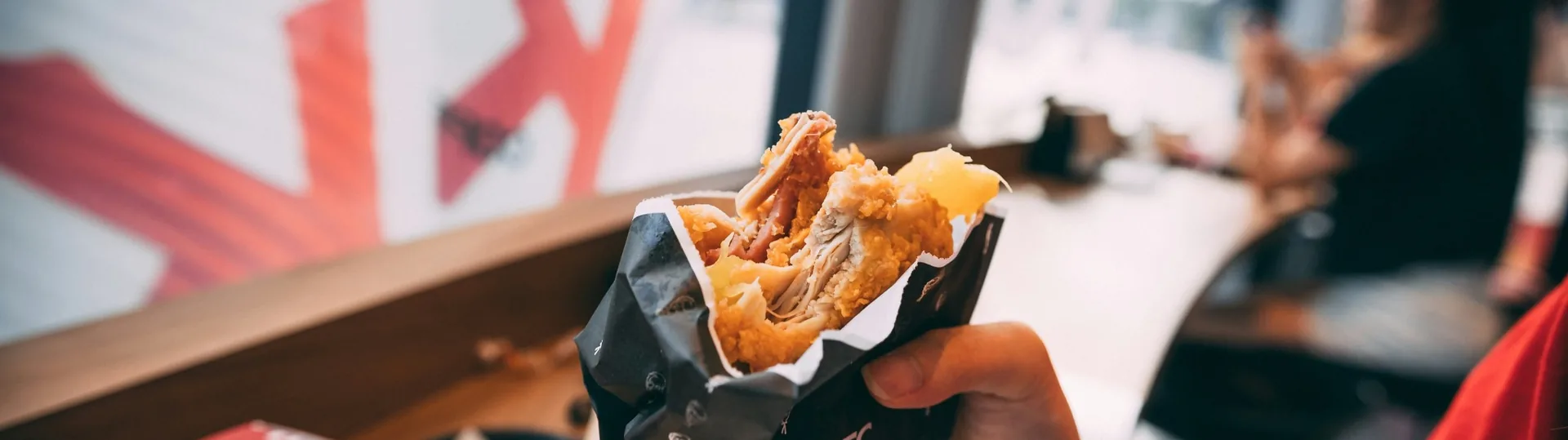 Customer holding KFC chicken wrap sandwich showcasing quick-service restaurant food quality