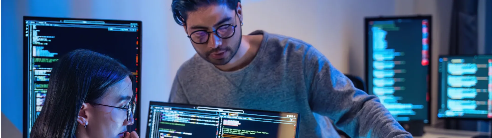 Two software developers collaborating on debugging code at computer workstation