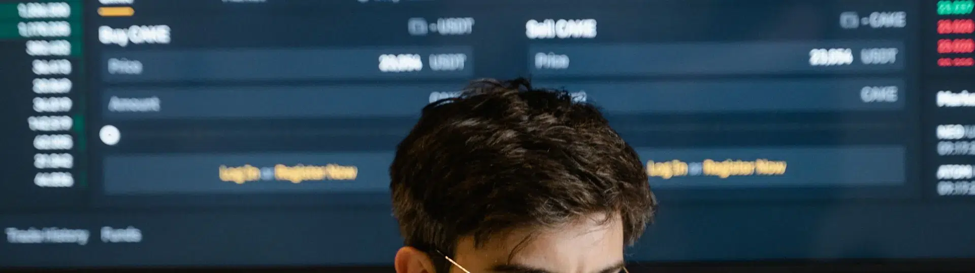 Financial analyst monitoring trading data and market performance on multiple screens