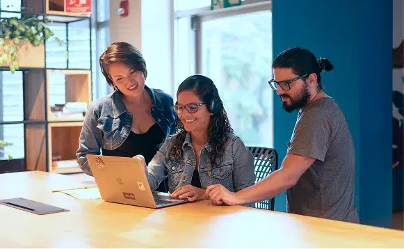 Engineers collaborating on AI project around laptop