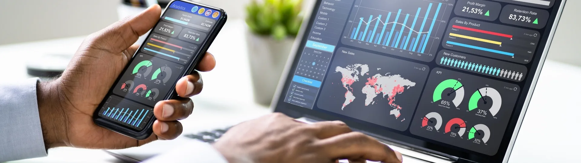 Business analyst using mobile and laptop to review analytics dashboards with KPI metrics