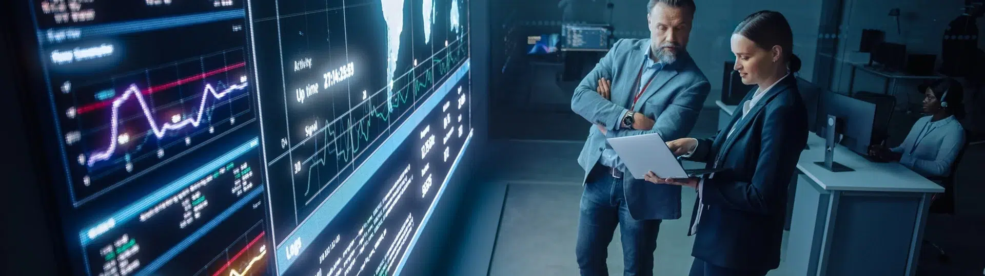 CIO and colleague reviewing live data analytics on a large digital display wall in a technology operations center