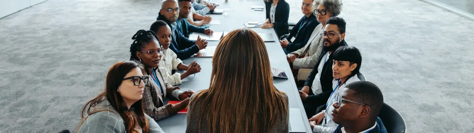 Diverse leadership team seated around a long conference table in a strategy discussion about workforce restructuring