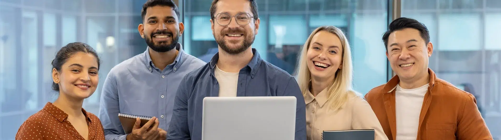 Diverse team of five tech professionals smiling together in a modern office representing the global engineering talent landscape