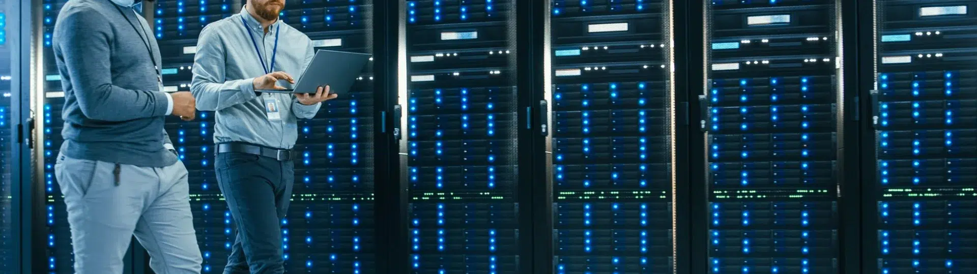 IT engineers reviewing server infrastructure configuration with a laptop in a data center