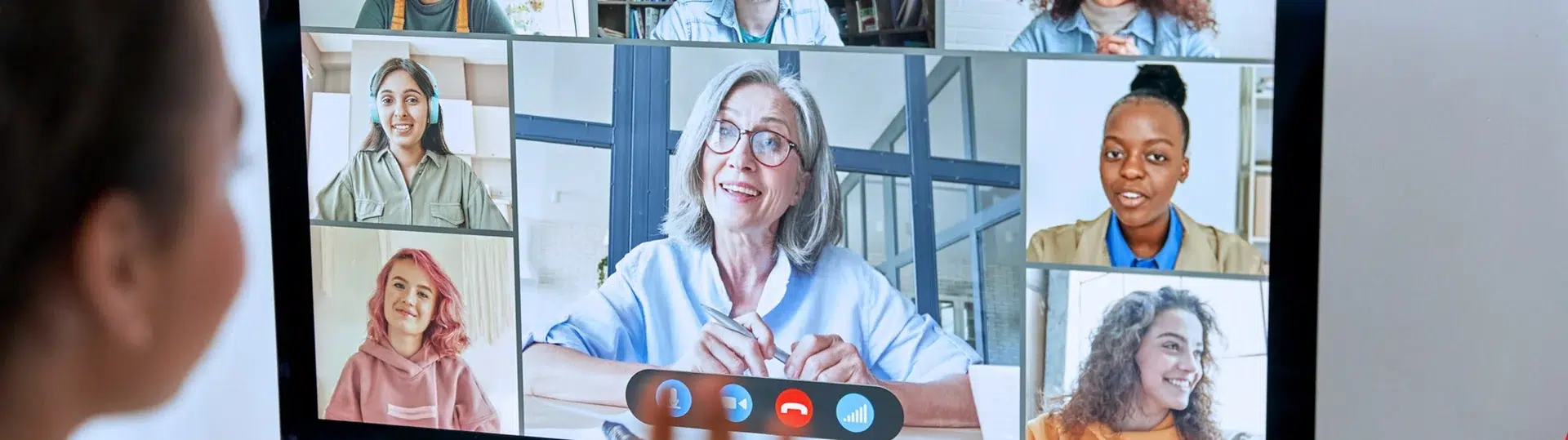 Professional waving at remote colleagues displayed on a large monitor during a video collaboration session