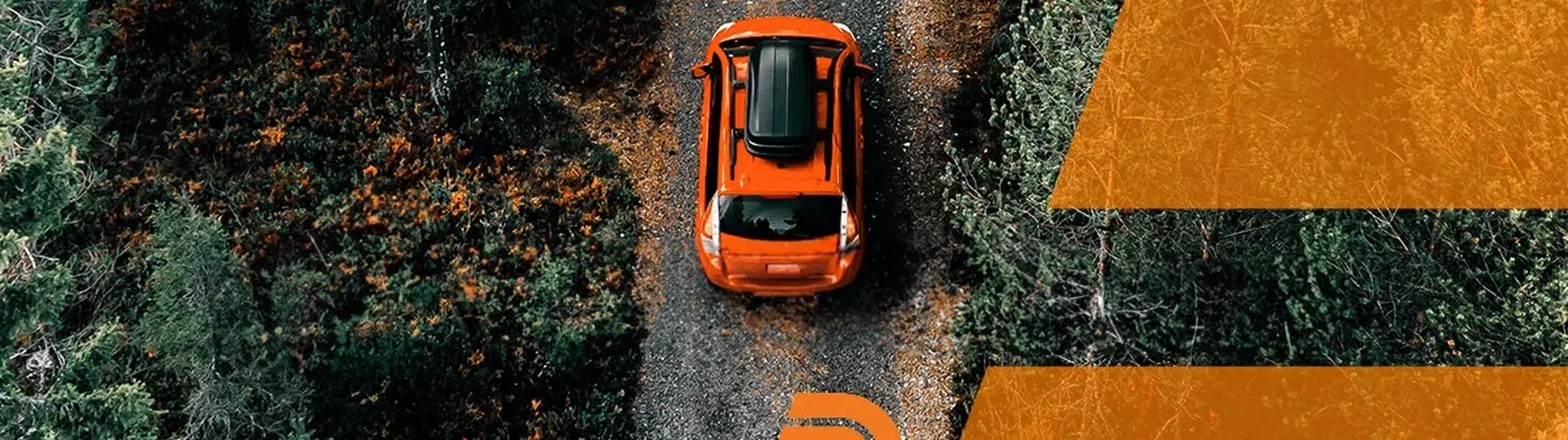 Aerial view of orange car driving on a forest road, representing CarParts.com's digital transformation journey