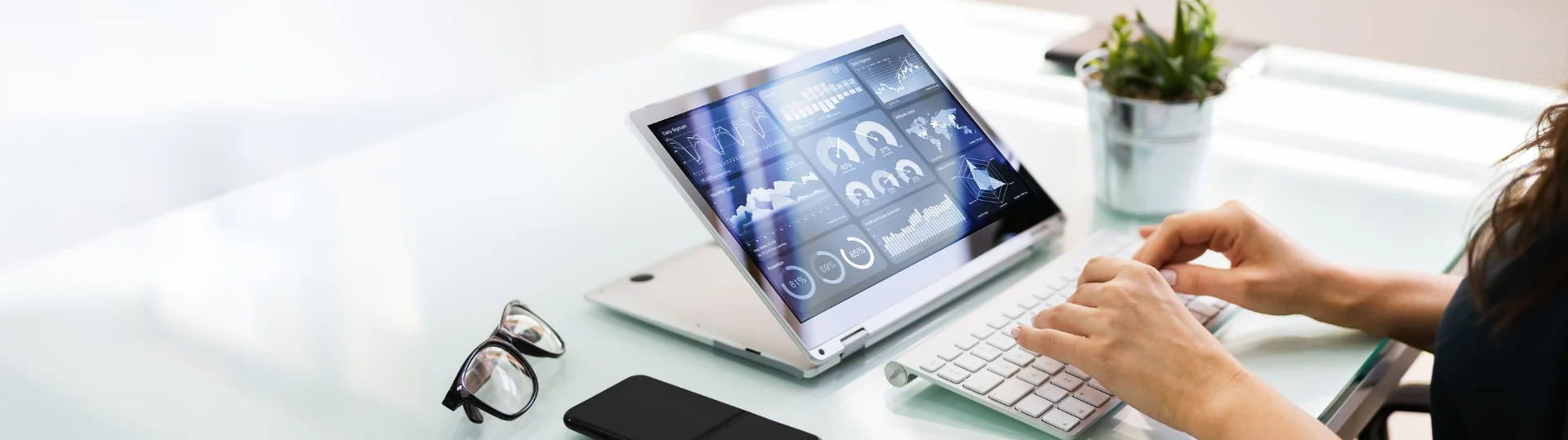 Analyst working on a laptop with a business intelligence dashboard displaying analytics and data visualizations