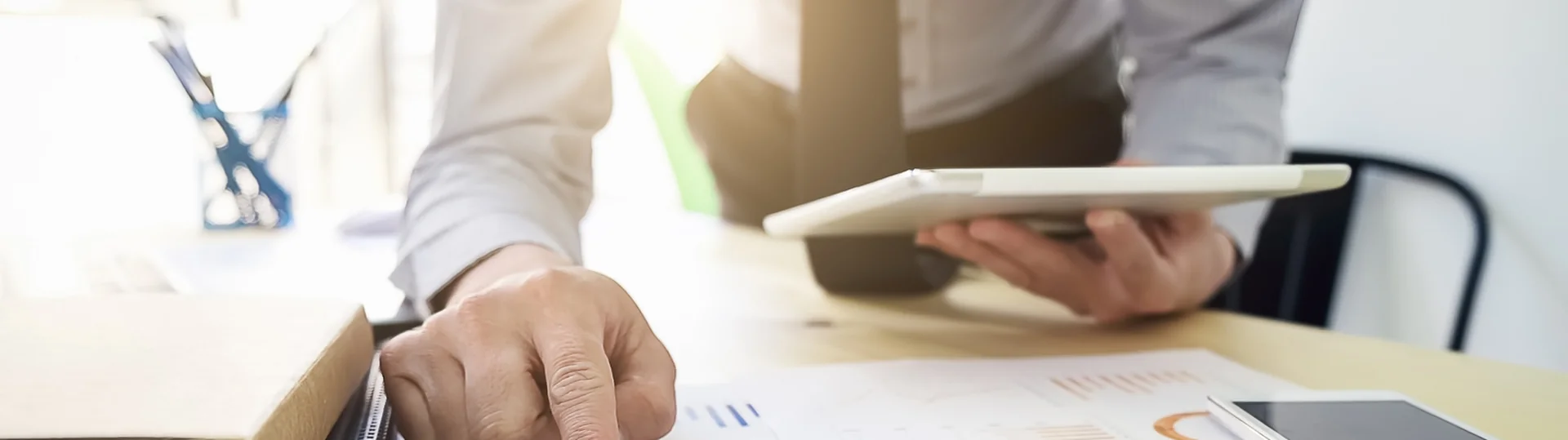 Business analyst reviewing printed charts and graphs while holding a tablet