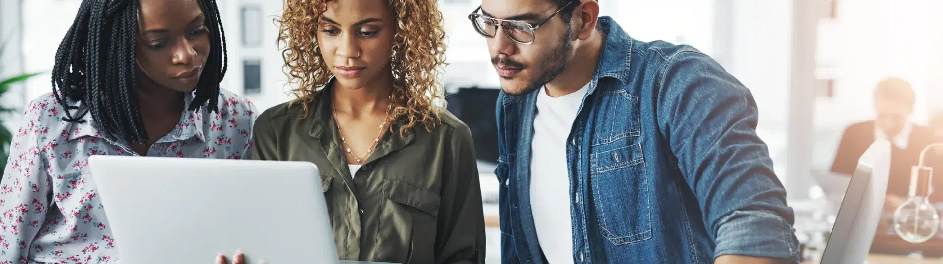 Three cloud professionals collaborating and reviewing deployment results on a laptop