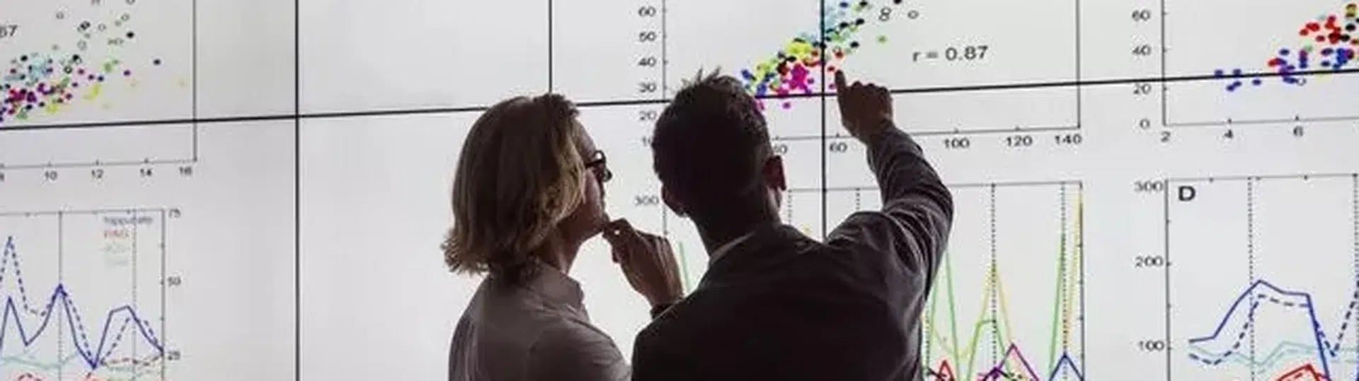 Data analysts reviewing analytics charts on large display screen