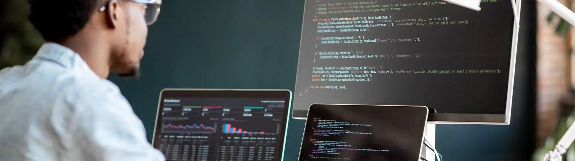 Developer working at a multi-monitor setup with code and analytics dashboards on screen