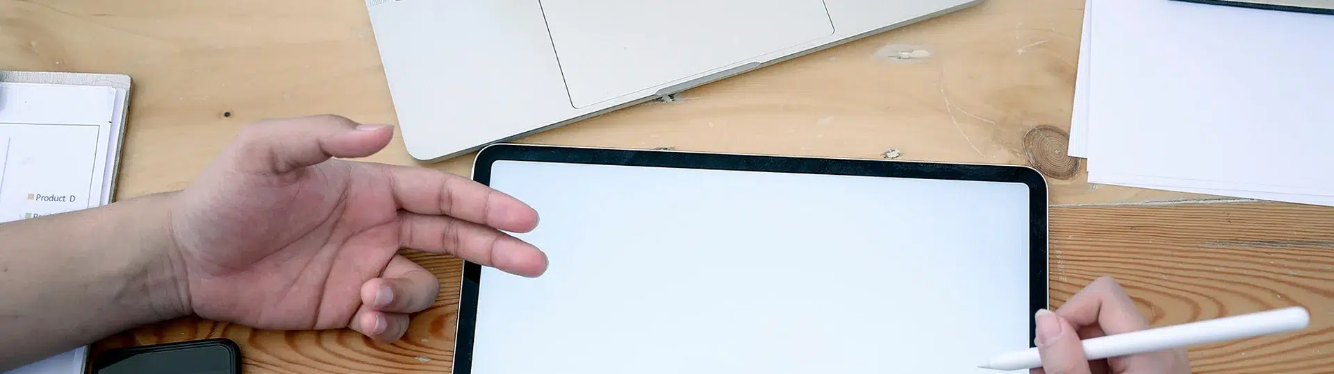 Developer using tablet with Apple Pencil and laptop on wooden desk for front-end development work