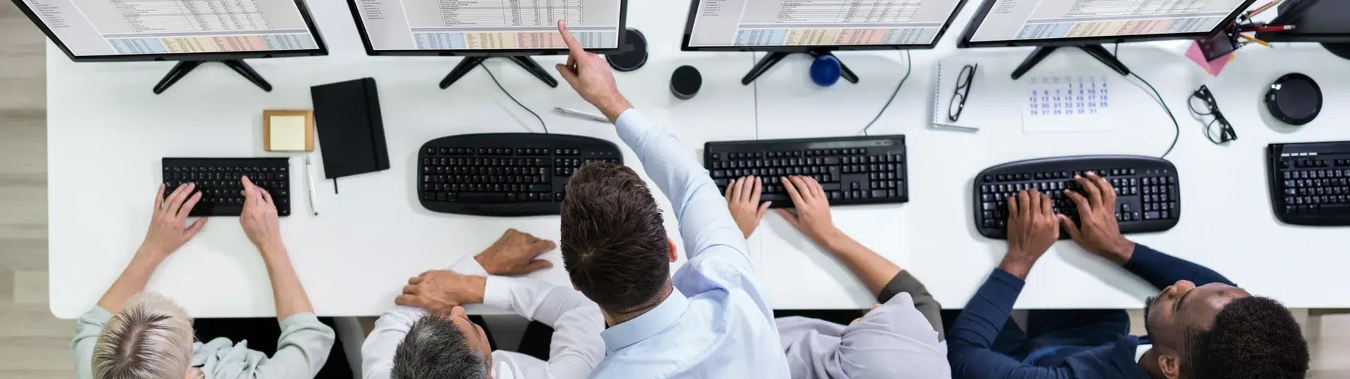 Overhead view of a development team working at workstations with multiple monitors