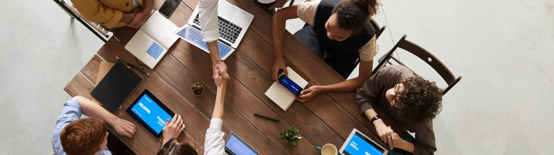 Overhead view of a diverse team collaborating around a table with laptops and tablets during a meeting