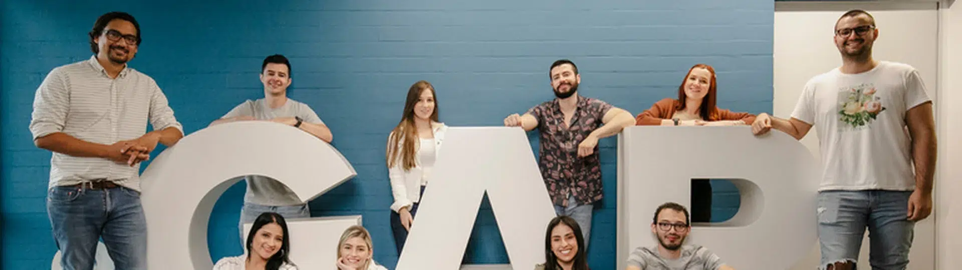 GAP team members posing with large 3D GAP letters in a modern office representing the company's collaborative culture