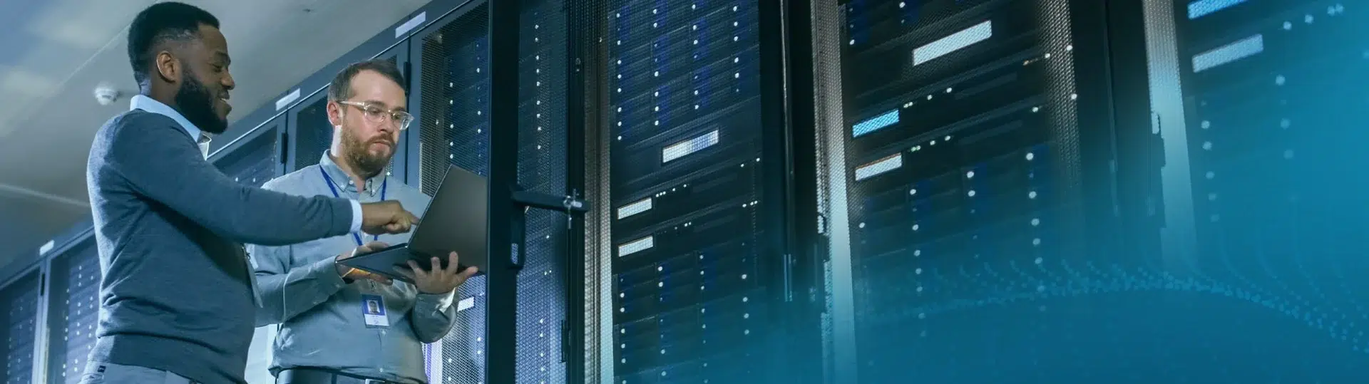 IT engineers reviewing server infrastructure with a laptop in a modern data center