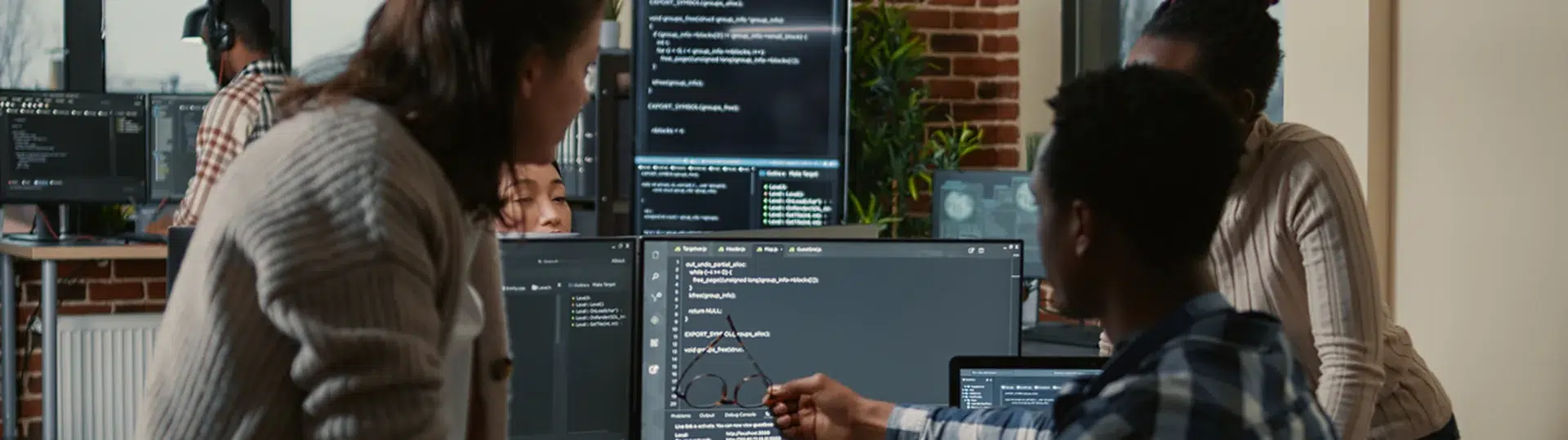 Diverse software development team collaborating at multi-monitor workstations