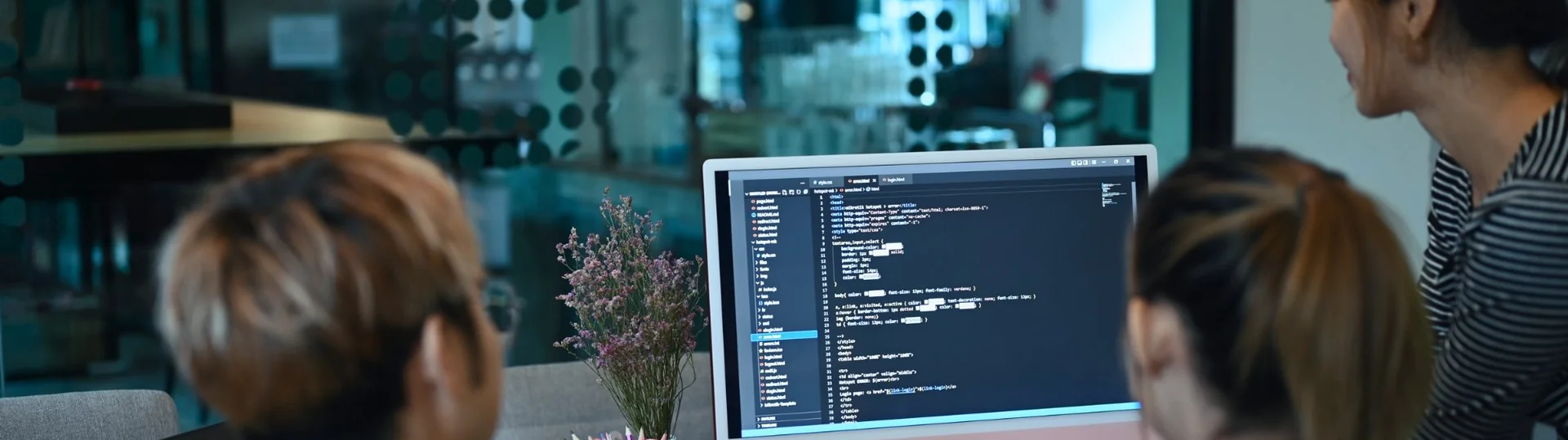 Software engineering team reviewing code together on desktop monitors in a modern development environment