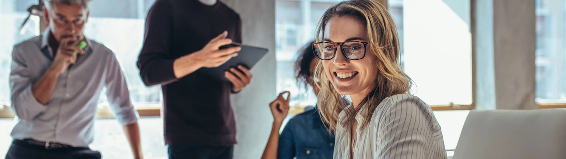 Woman at laptop with team collaborating in office environment