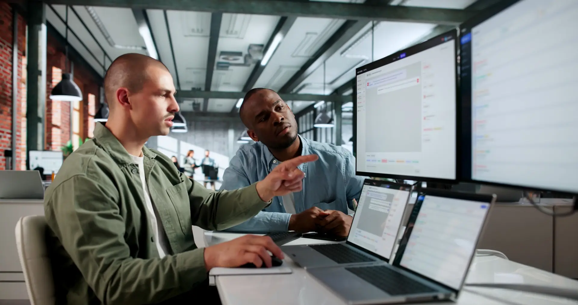 Two colleagues working through a problem together at a shared screen